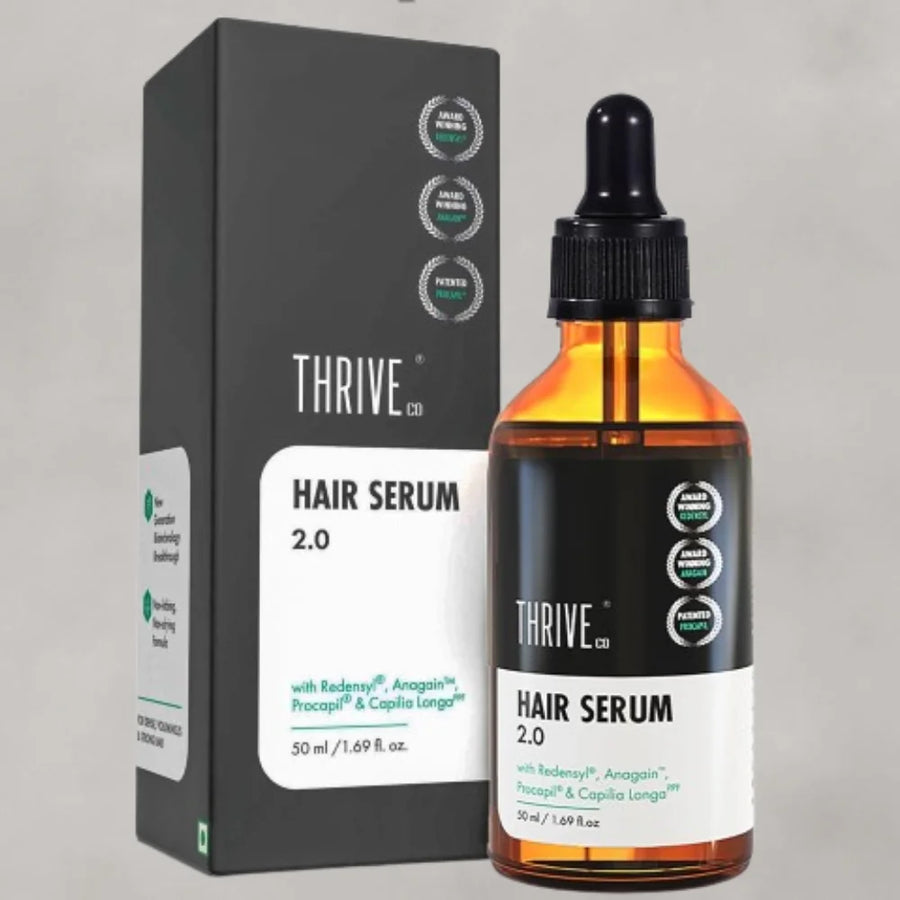 Thrive Co. Hair Serum 2.0 50ml bottle with a black dropper, next to its grey box highlighting ingredients Redensyl, Anagain, Procapil, & Capilia Longa.
